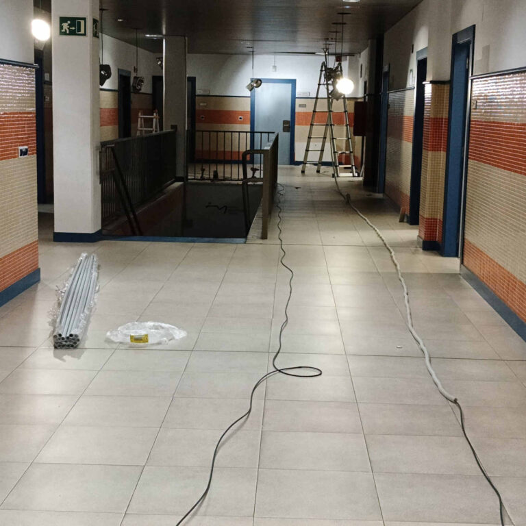 Tendido de fibra óptica y tubo corrugado en paralelo por el suelo del pasillo principal, preparando la canalización antes de su instalación definitiva en techo