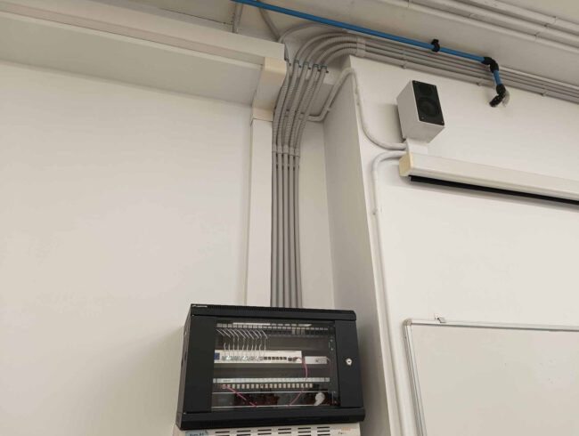 Canalizaciones verticales realizadas con tubo rígido de PVC y tramos de tubo flexible industrial para el guiado ordenado del cableado desde el armario rack hacia las aulas