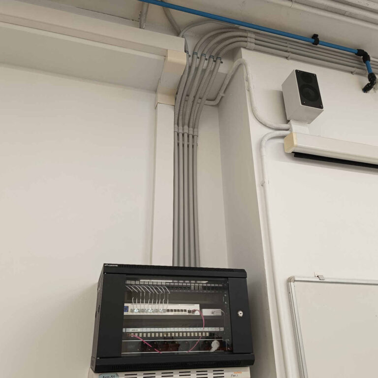 Canalizaciones verticales realizadas con tubo rígido de PVC y tramos de tubo flexible industrial para el guiado ordenado del cableado desde el armario rack hacia las aulas