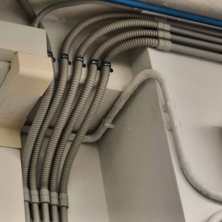 Detalle de la combinación de tubo rígido de PVC, tubo flexible industrial y manguitos de unión para salvar obstáculos geométricos durante la canalización del cableado