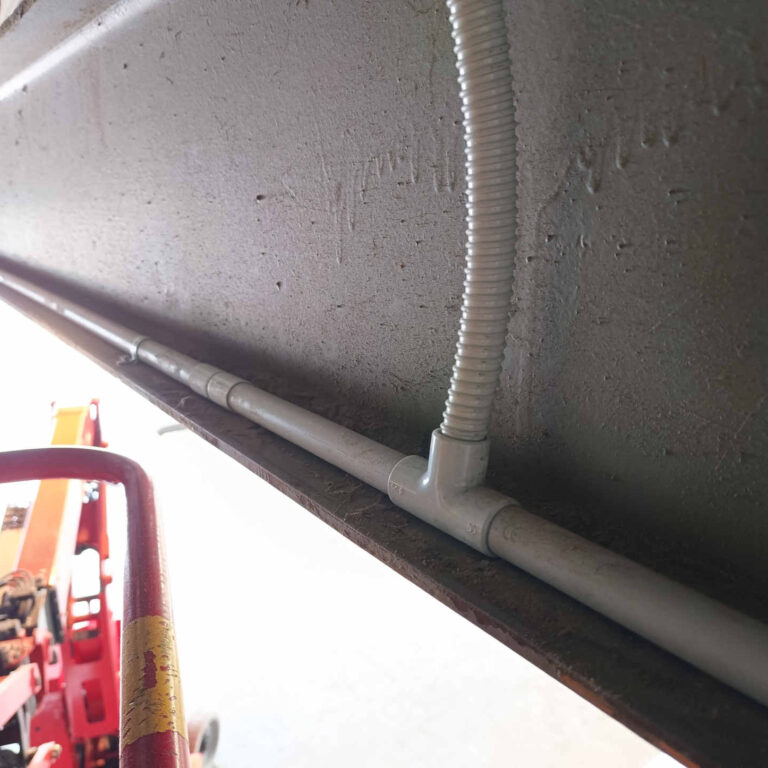 Canalización de cableado de videovigilancia mediante tubo rígido y corrugado con pieza en T instalada sobre viga aérea de nave industrial