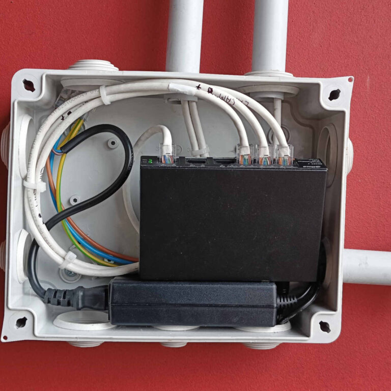 Interior de caja de derivación con switch PoE intermedio y acometidas de cableado UTP organizadas para cámaras de videovigilancia