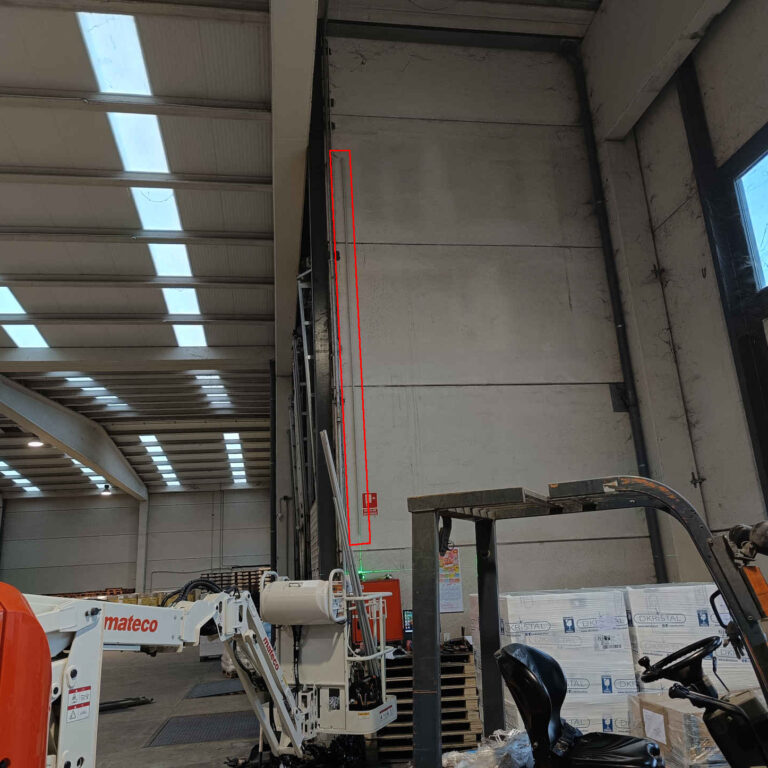 Canalización vertical con tubo rígido de PVC instalada en nave logística siguiendo el trazado marcado por láser para el cableado de videovigilancia