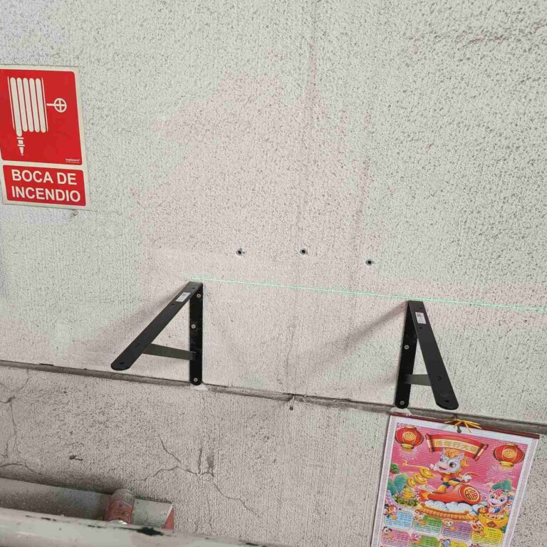 Colocación de escuadras metálicas para aumentar la robustez y estabilidad del anclaje del armario de seguridad en nave industrial