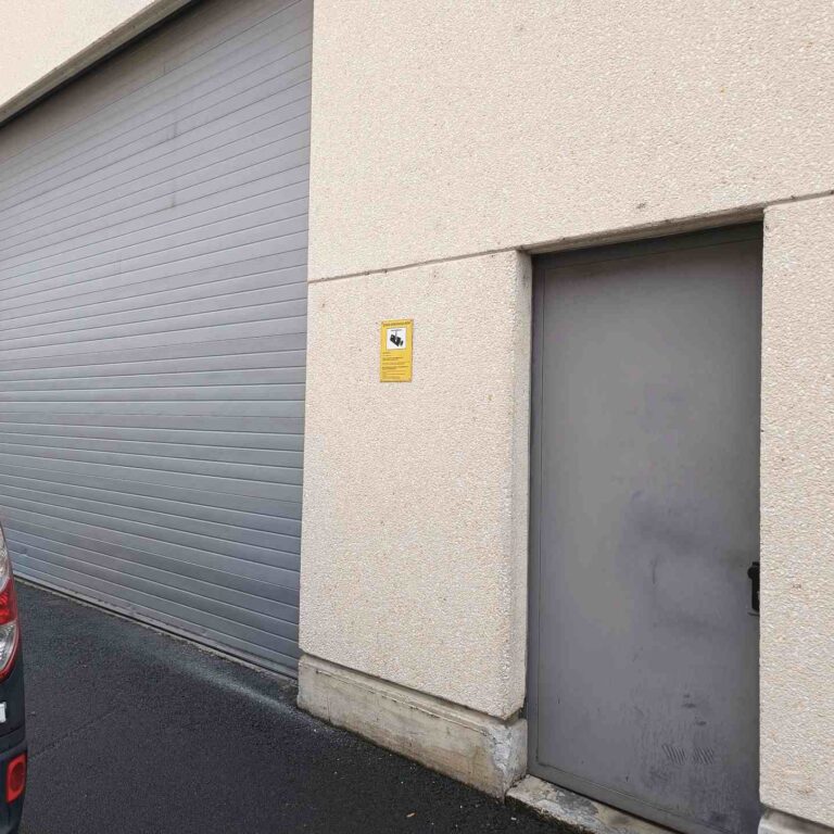 Cartel informativo de videovigilancia conforme al RGPD instalado en el acceso trasero de la nave industrial para cumplir con la normativa de protección de datos