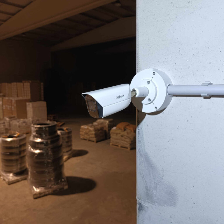 Cámara de videovigilancia Dahua instalada sobre pilar interior de nave industrial, mostrando el entorno monitorizado en condiciones de escasa iluminación