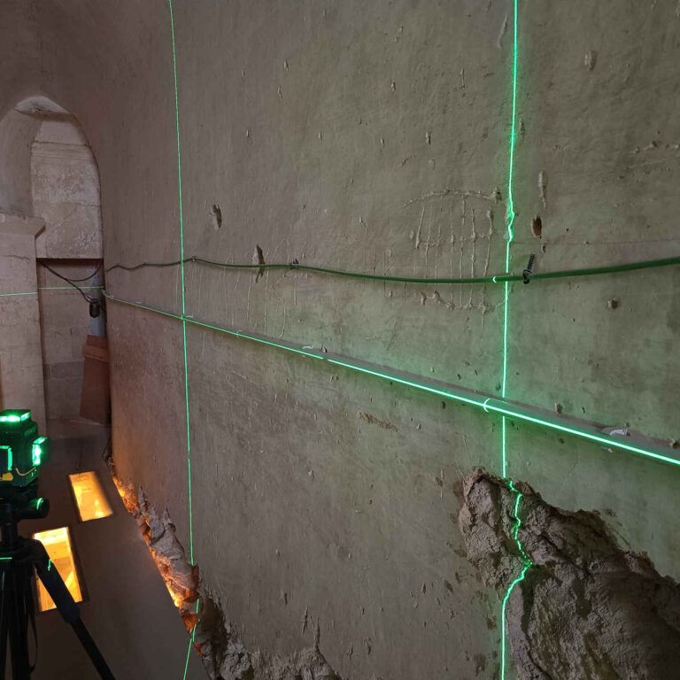 Instalación de tubo rígido PVC alineado en pared antigua con nivel láser para cableado estructurado