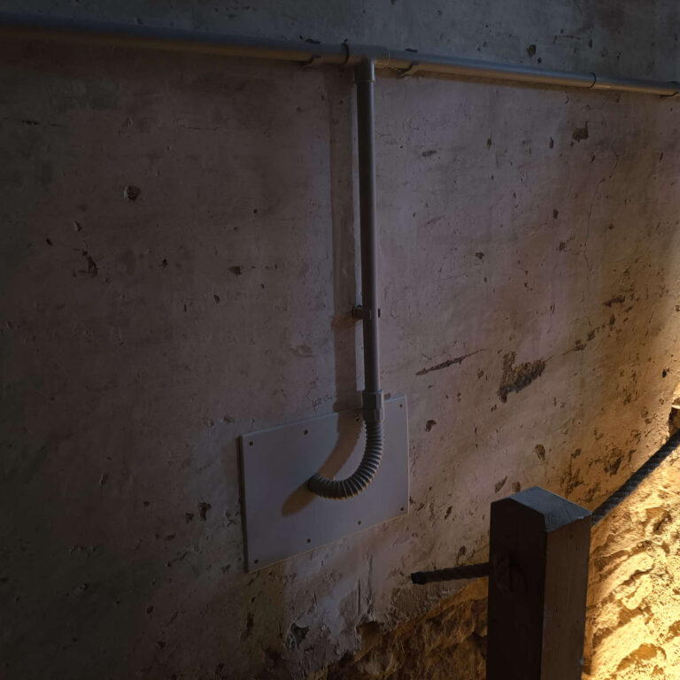 Derivación en T con bajada vertical de tubo PVC para paso de cableado en muro de piedra