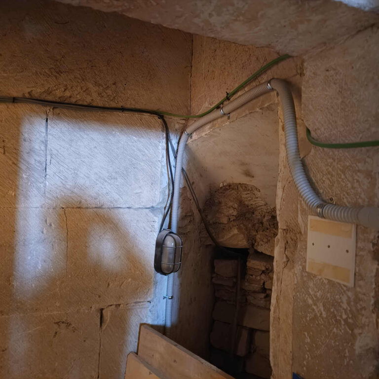 Canalización eléctrica con tubo flexible y derivación en pared de piedra irregular