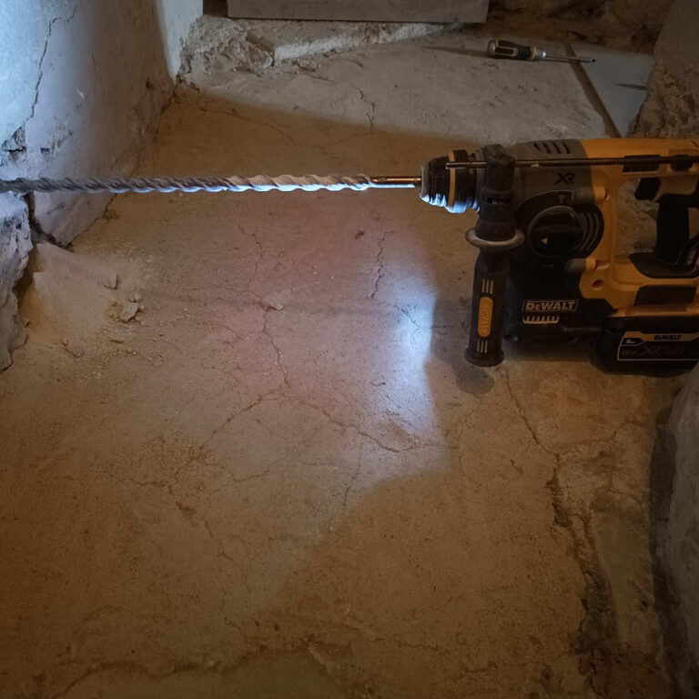 Taladro con broca de 60 cm perforando muro de piedra en espacio reducido