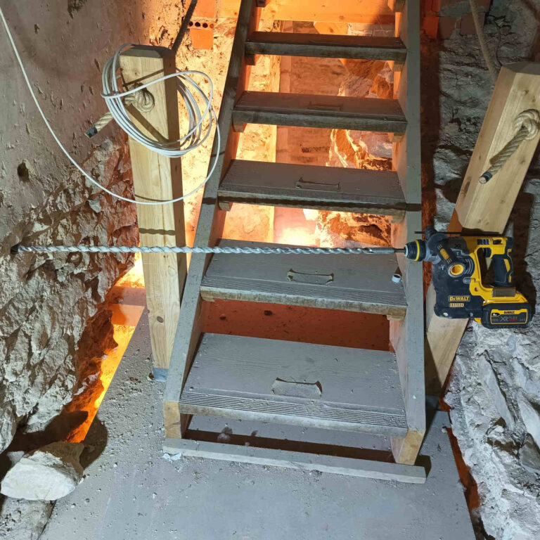 Taladro profesional con broca de 1 metro atravesando muro grueso en edificio histórico