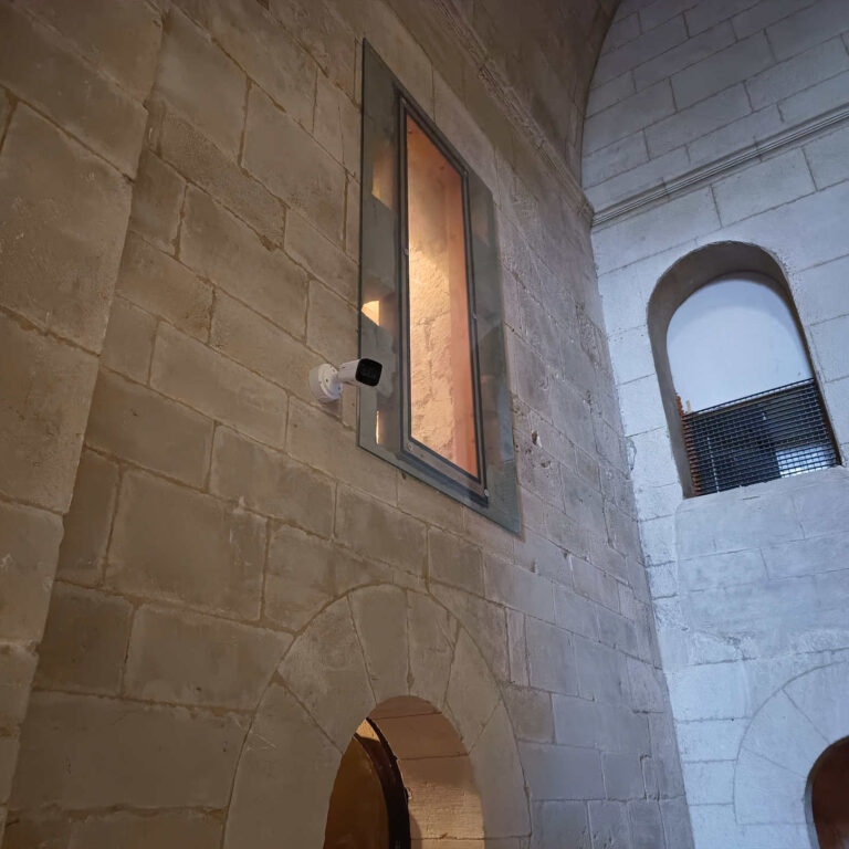 Cámara de videovigilancia instalada en pared de piedra en interior de iglesia