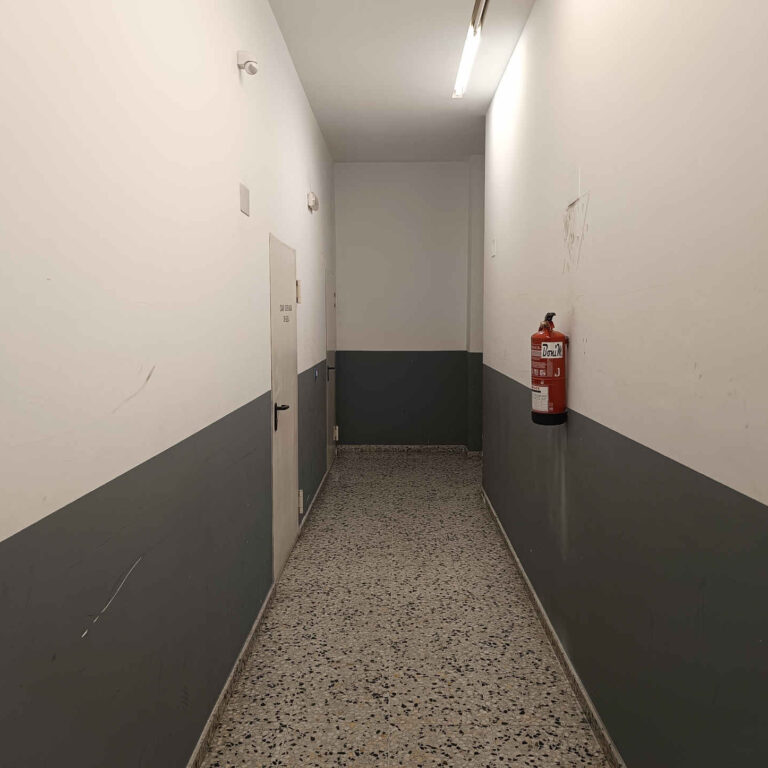 Pasillo interior de una comunidad de vecinos con marcas y desperfectos antes de la instalación de cámaras de seguridad
