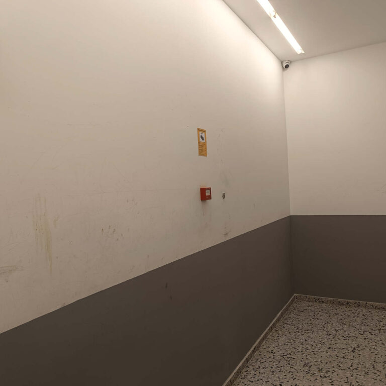 Cámara de seguridad instalada en una zona secundaria del portal junto a señalización disuasoria de videovigilancia