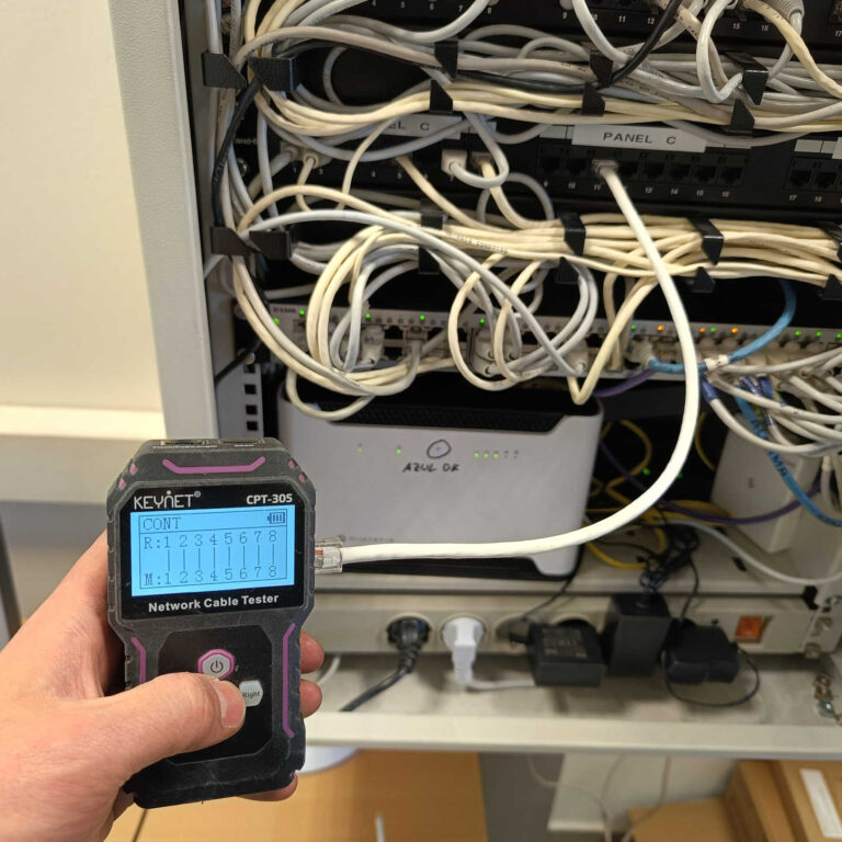 Tester de red comprobando continuidad y conexión Ethernet entre la nave industrial y el armario rack de comunicaciones