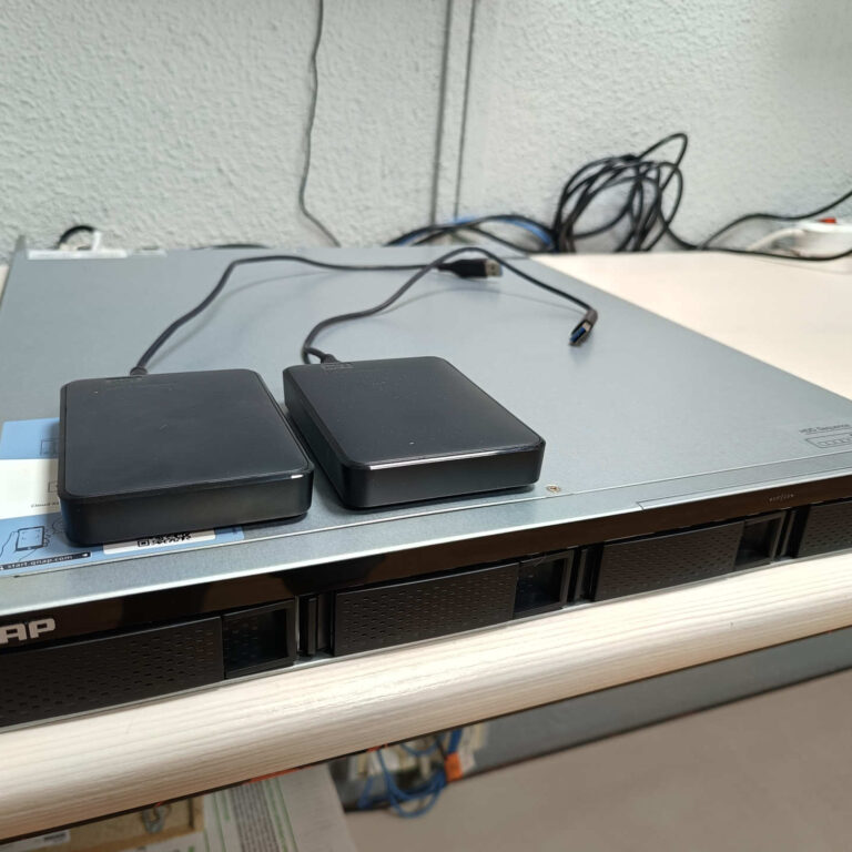 Servidor NAS QNAP recibido en las instalaciones de InfoRepara junto a discos duros externos para copia de seguridad y recuperación de datos