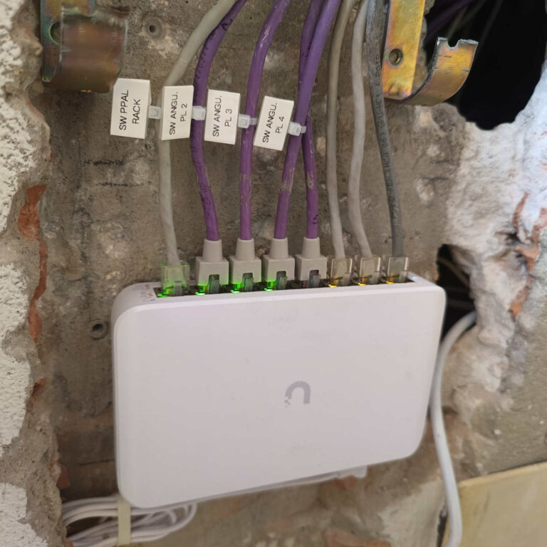 Nuevo switch de distribución Ubiquiti UniFi instalado en una caja de comunicaciones, con el cableado reorganizado y los enlaces principales correctamente identificados mediante etiquetas.