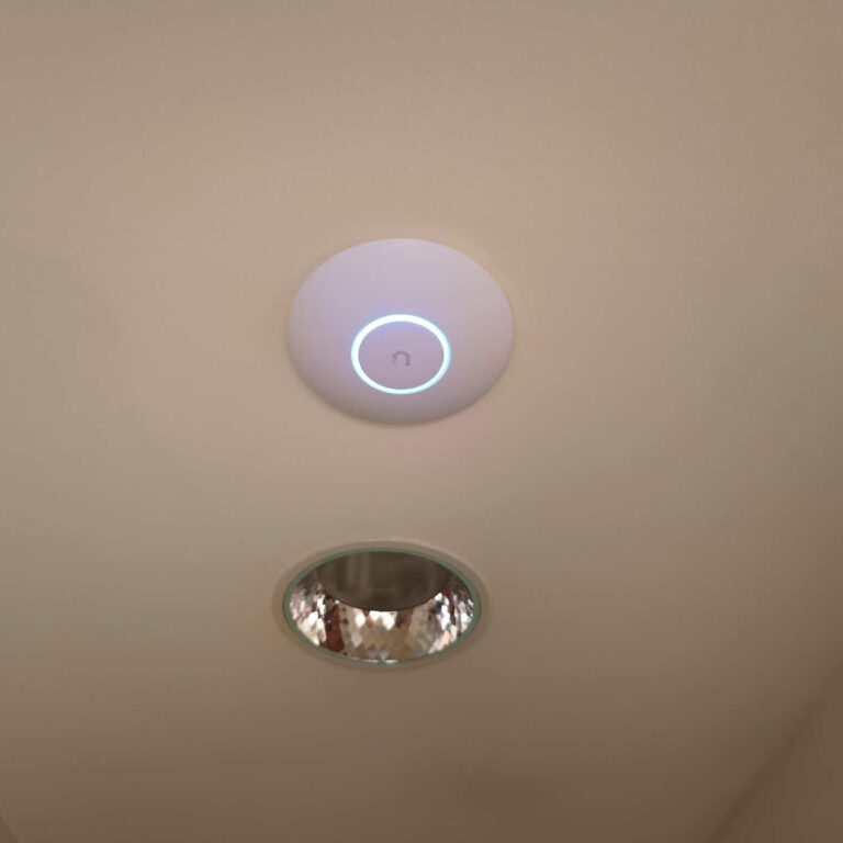 Punto de acceso WiFi Ubiquiti UniFi instalado en el techo del pasillo de la residencia de estudiantes para proporcionar cobertura inalámbrica de alta velocidad y un roaming fluido entre plantas